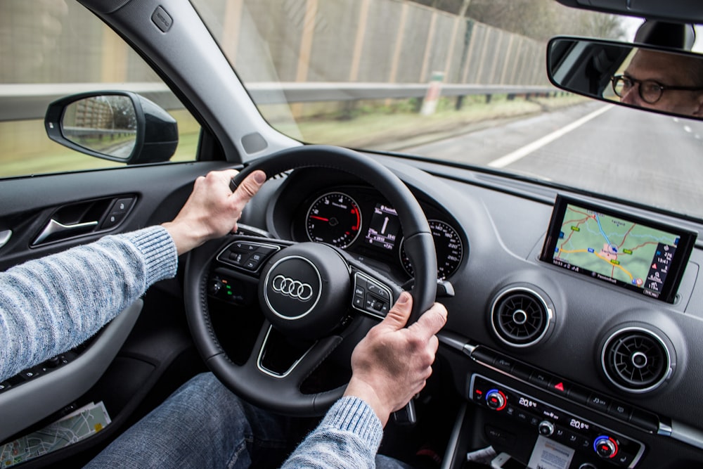 homem dirigindo carro Audi na estrada de asfalto