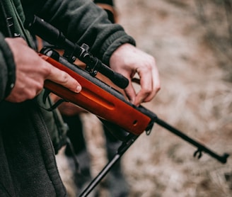 person loading brown and black sniper rifle