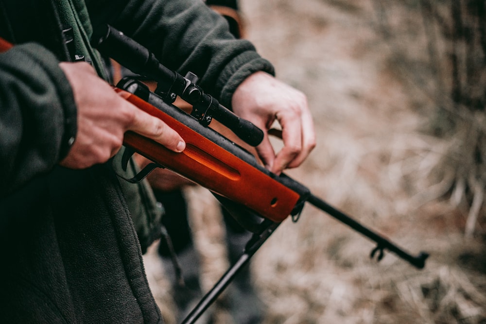 Persona cargando rifle de francotirador marrón y negro