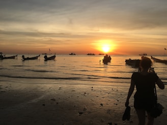 A serene sunset over the calm waters of Muro Alto beach with colorful boats anchored near the shore.
