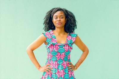 A plus-size Hispanic woman smiling confidently in a vibrant custom dress.