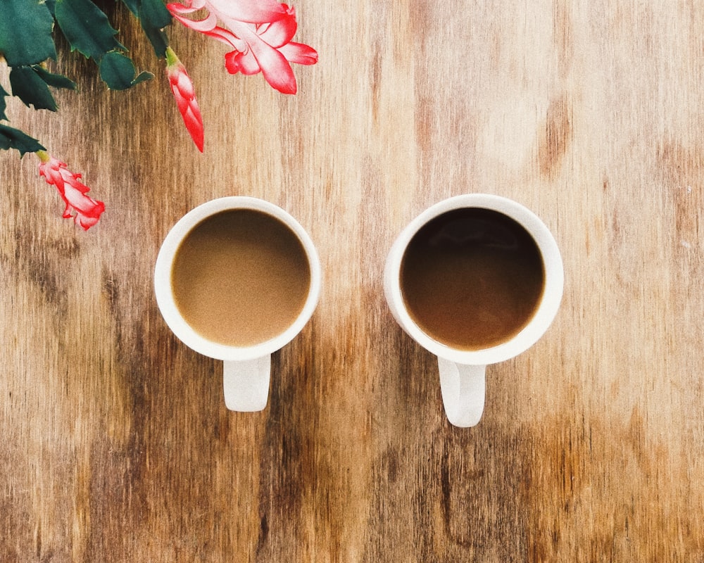 two white ceramic cups on wooden surface