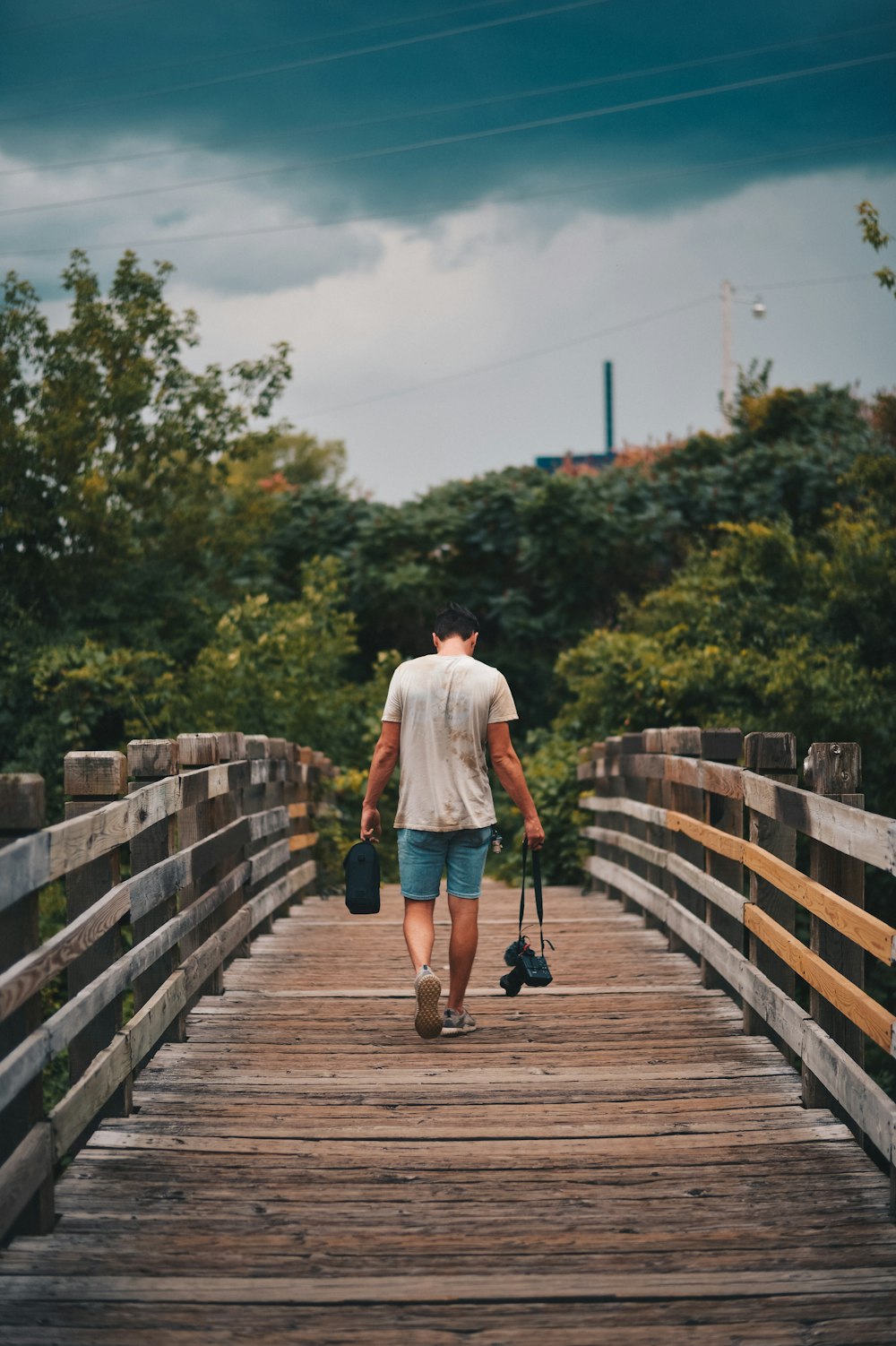 man walking on brown wooden bridge