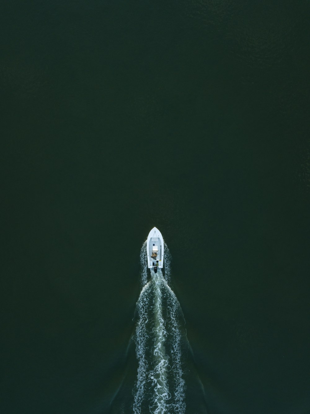 weißes Motorboot am Gewässer und verlässt die Wasserspur