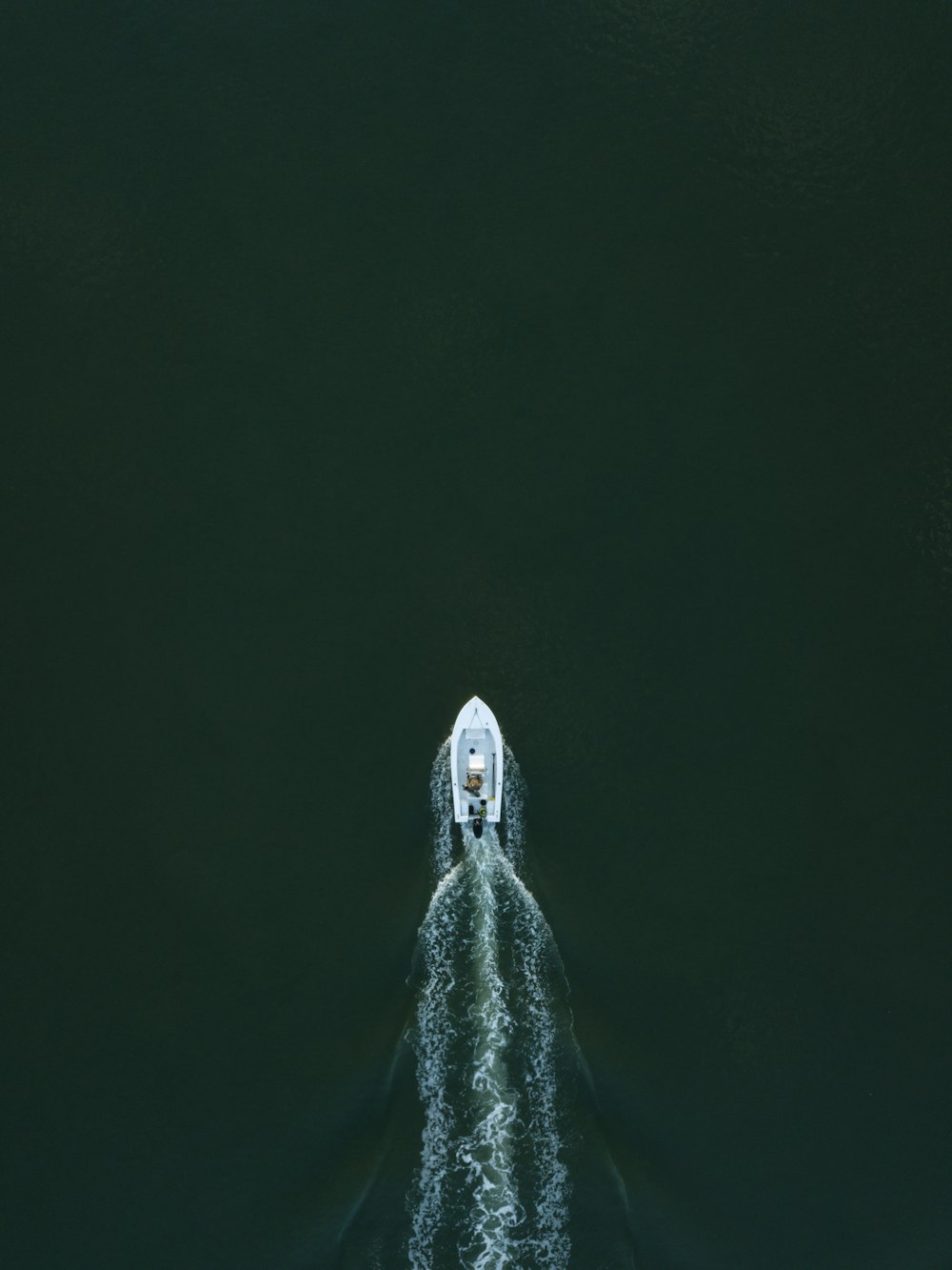 white powerboat at body of water leaving water trail