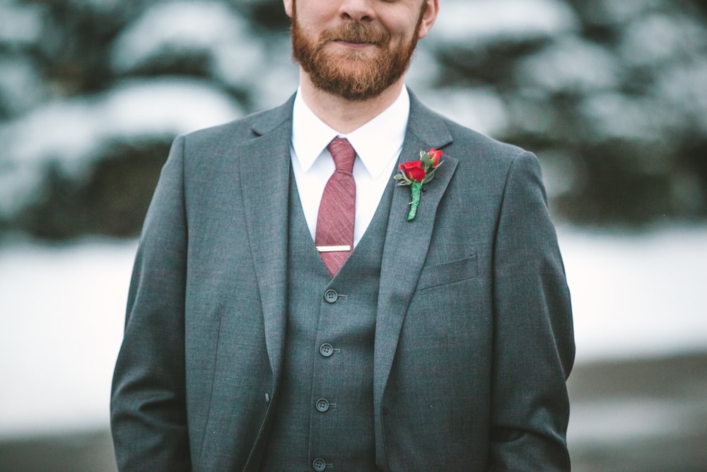 Hombre con blazer de solapa gris con muescas, chaleco gris y camisa de vestir blanca con botones rosas