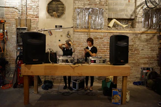 A candid backstage moment showing a DJ and a mentor deep in conversation amid festival equipment.