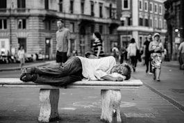 man sleeping on bench in the middle of the street