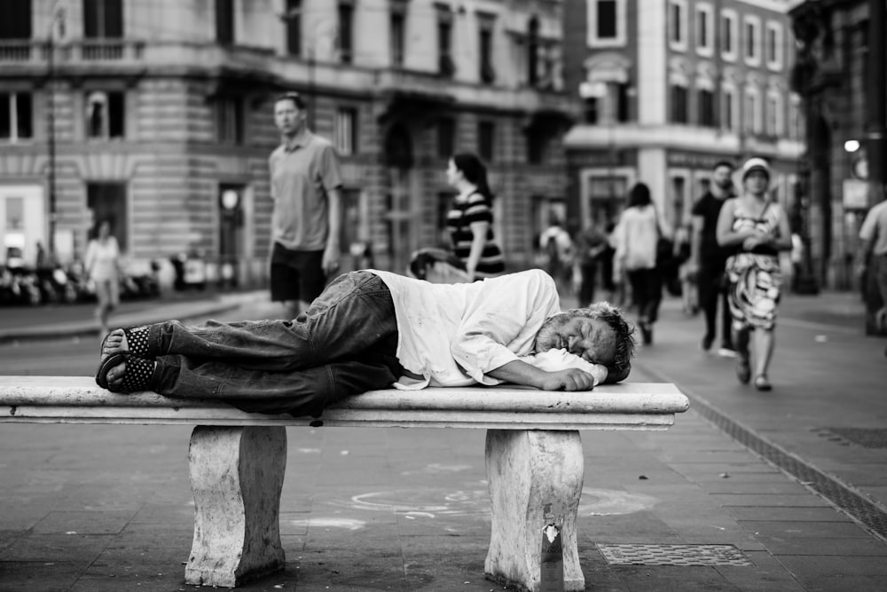 man sleeping on bench in the middle of the street