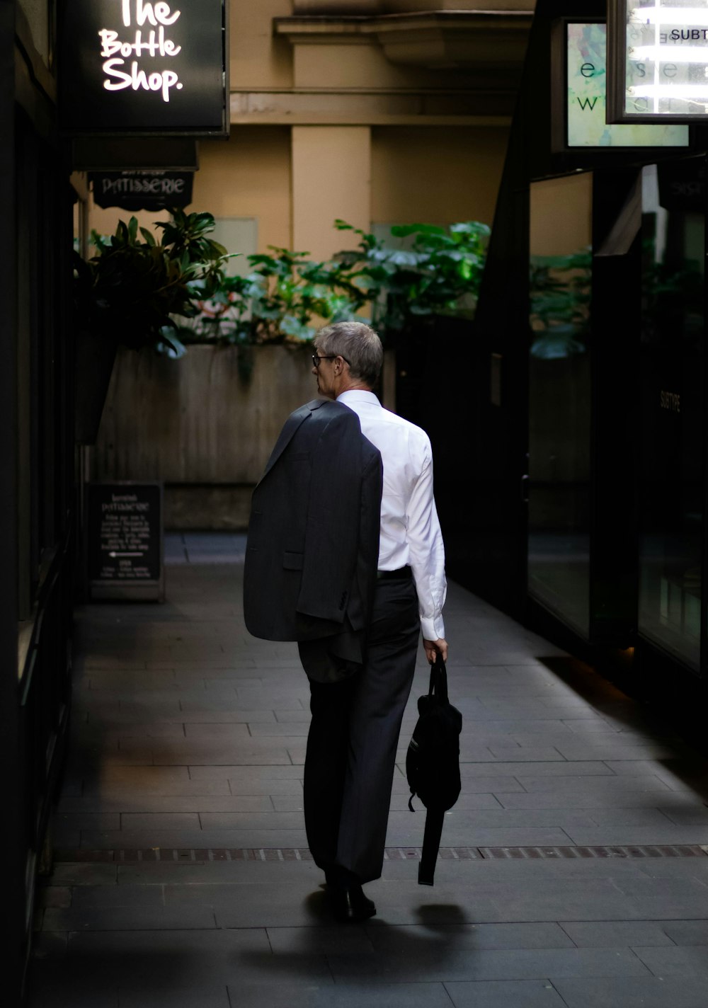 man holding black bag walking on road