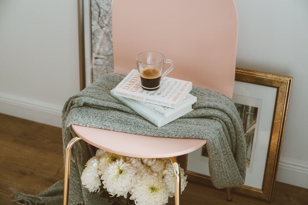 Tasse en verre transparent sur trois livres empilés à l’intérieur de la chambre