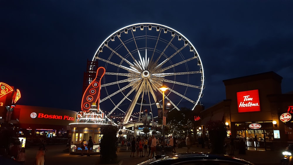 low angle of white Ferris wheel near bowling area under blue sky