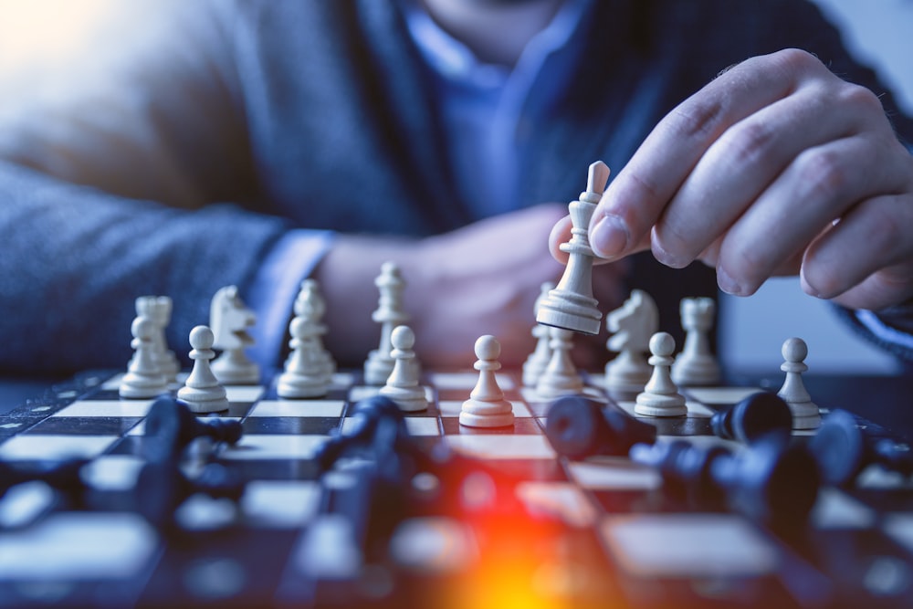 depth of field photography of man playing chess