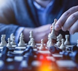 depth of field photography of man playing chess