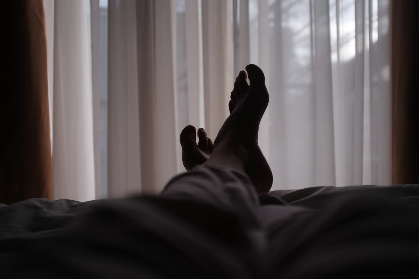 A person lying in a dark bedroom at night