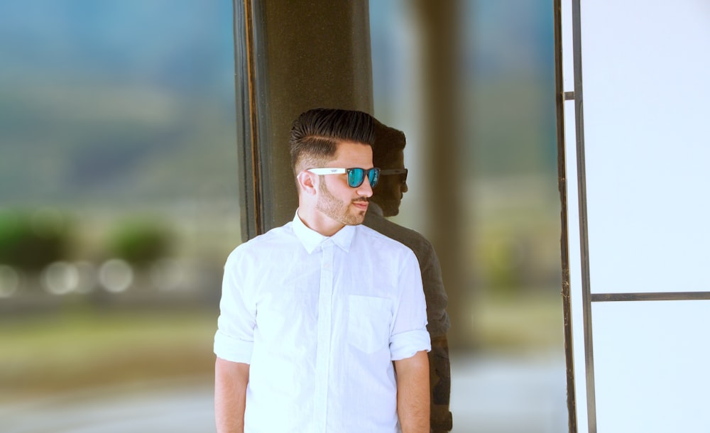 man leaning on glass wall during daytime