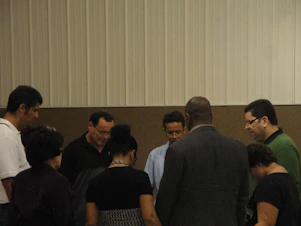 A diverse group of people gathered in a circle during a lively Bible study, sharing smiles and open Bibles.