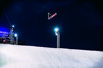 person on snowboard jumping above ramp