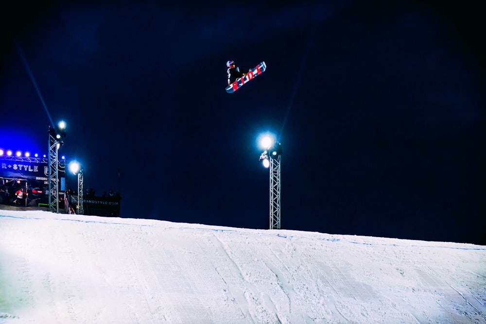 Person auf dem Snowboard springt über Rampe