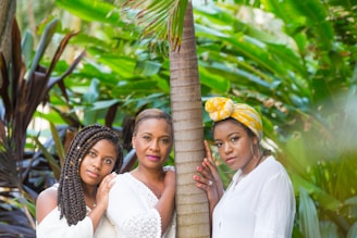 three women standing beside tree