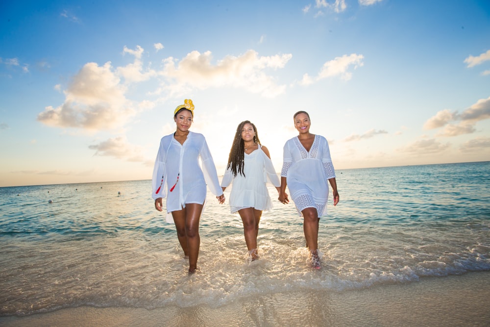 three women holding hands in seashore