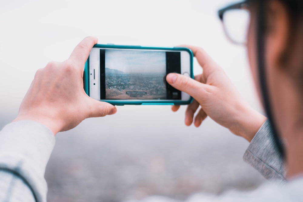 person holding iPhone and capturing photo