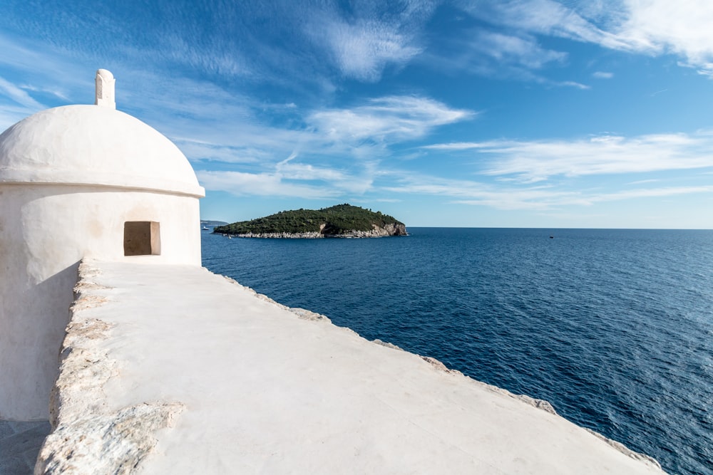 white concrete structure beside body of water