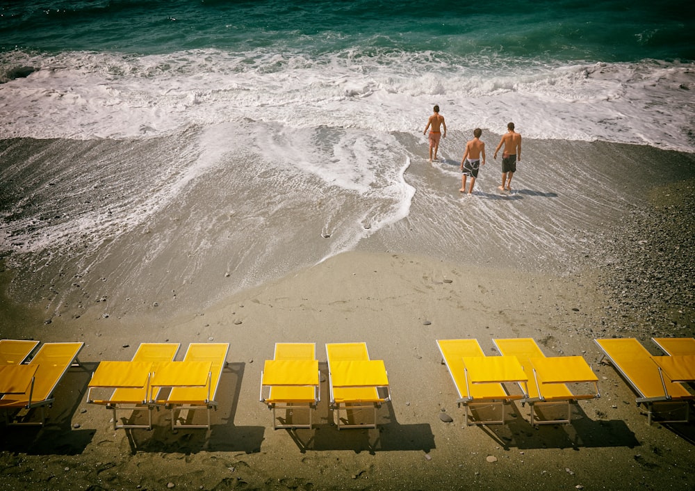 three people walking in seashore