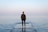 man standing on concrete dock facing sea