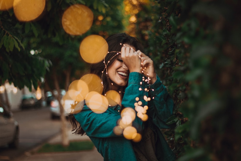 woman standing in front of green leafed plants with light bokeh