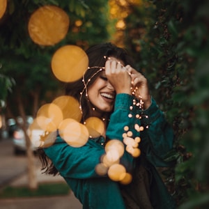 woman standing in front of green leafed plants with light bokeh