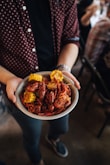 person holding bowl of shrimp with slice of corn dish
