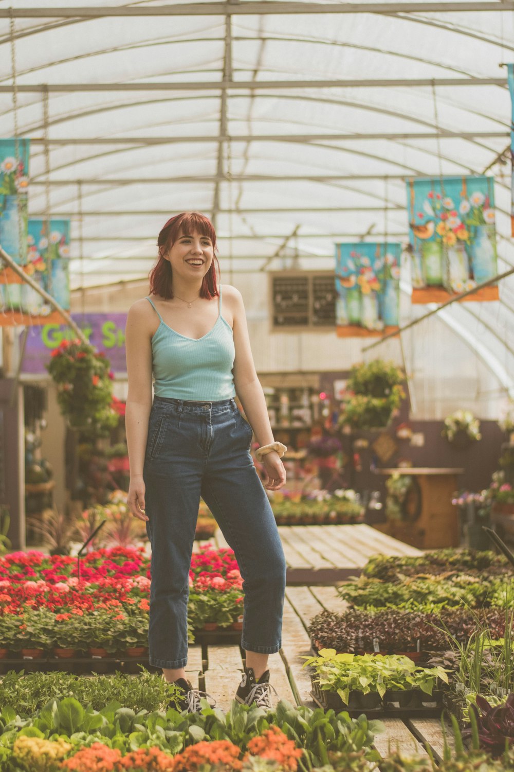 woman standing near flower pots inside greenhouse