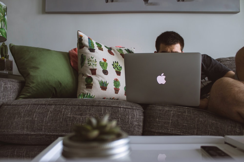 Mann mit MacBook saß auf dem Sofa