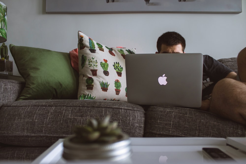 hombre usando MacBook se sentó en el sofá
