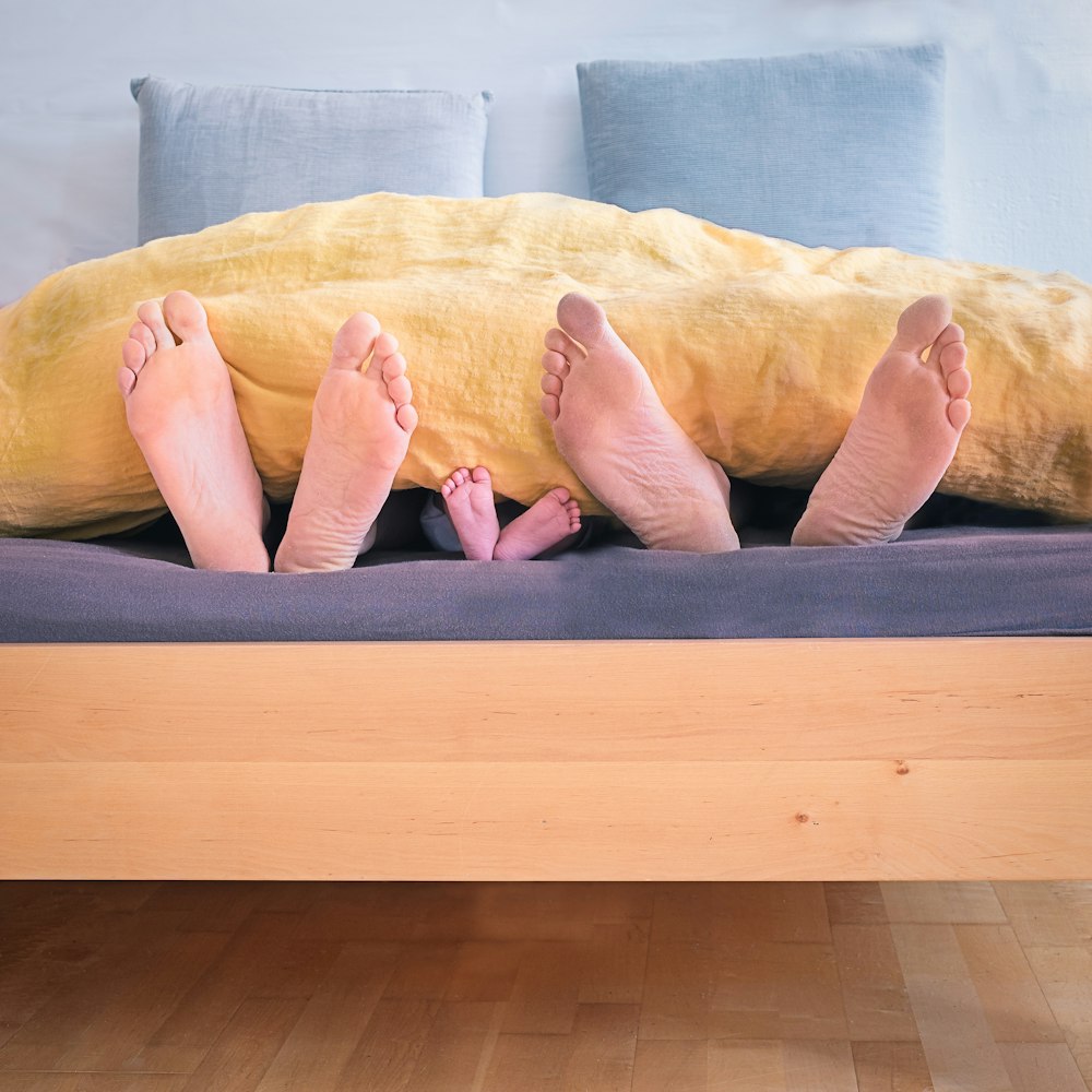 trois personnes sous une couverture de lit jaune