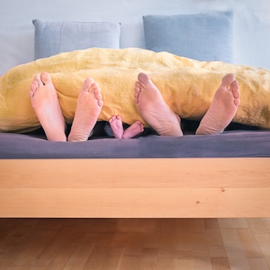 photography poses for family,how to photograph one
 and one —
 is three.; three people underneath yellow bed blanket