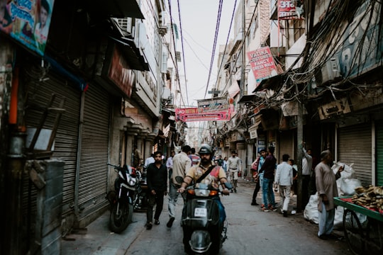 people in alley between buildings in Old Delhi India
