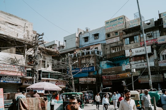 people walking on street in front of building under blue sky in Old Delhi India