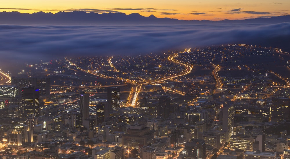 Una vista de una ciudad por la noche desde arriba de las nubes