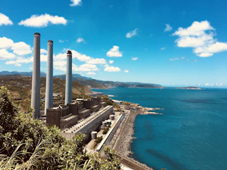 gray and brown factory near sea under blue sky