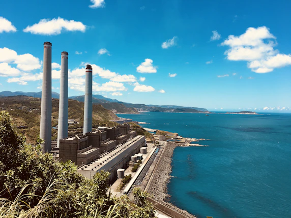 gray and brown factory near sea under blue sky