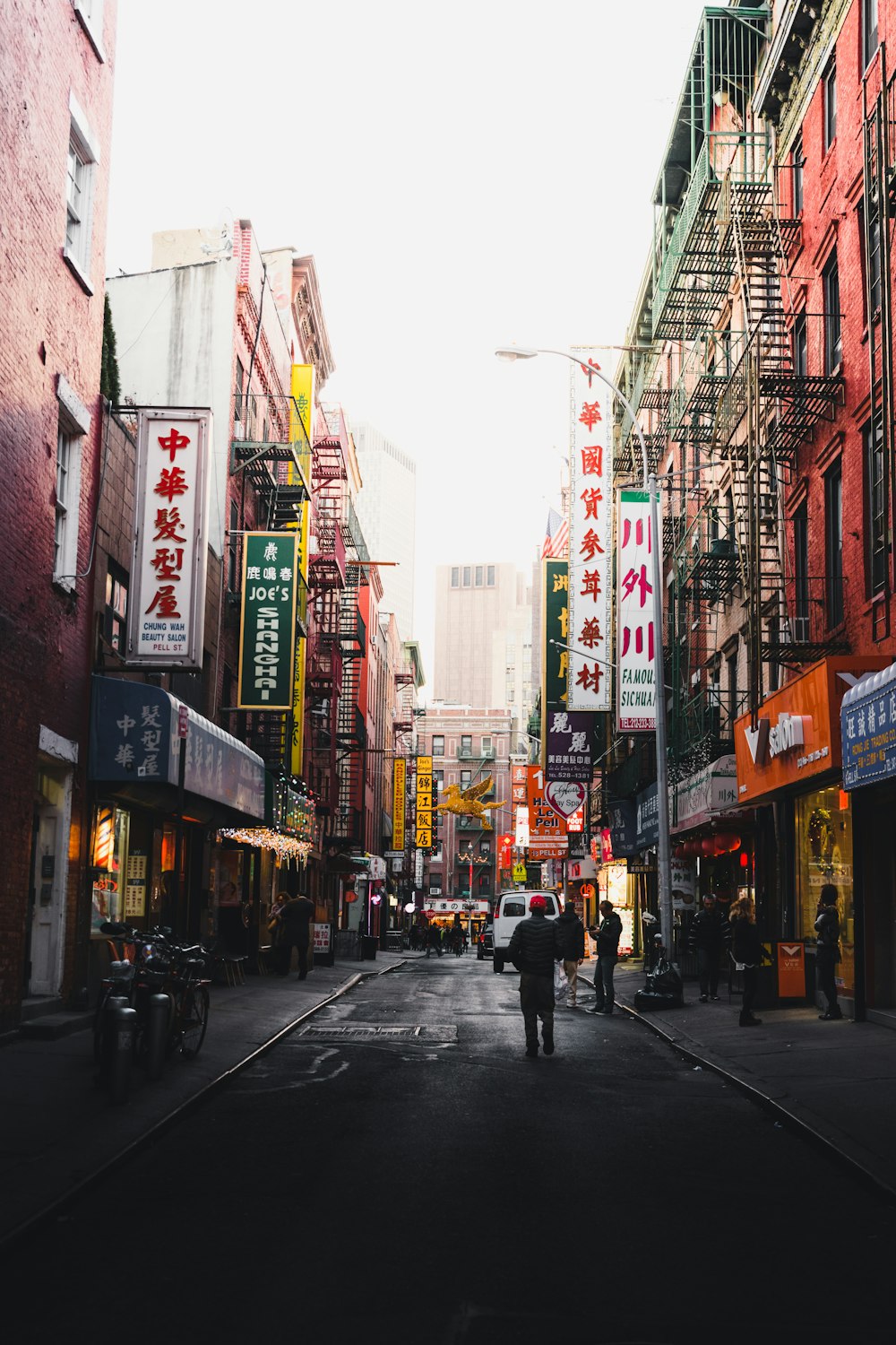 fotografia de pessoas andando na rua entre edifícios