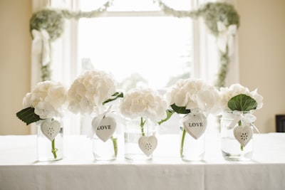 white flowers in glass jars fur teams background