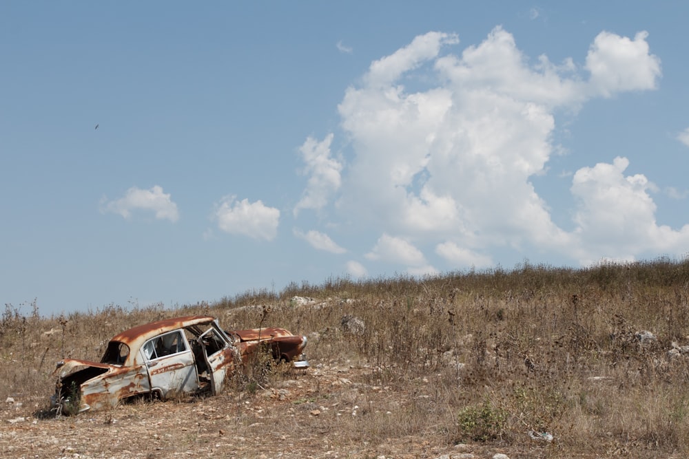 Foto einer zerstörten Limousine auf braunem Grasfeld unter strahlend blauem Himmel