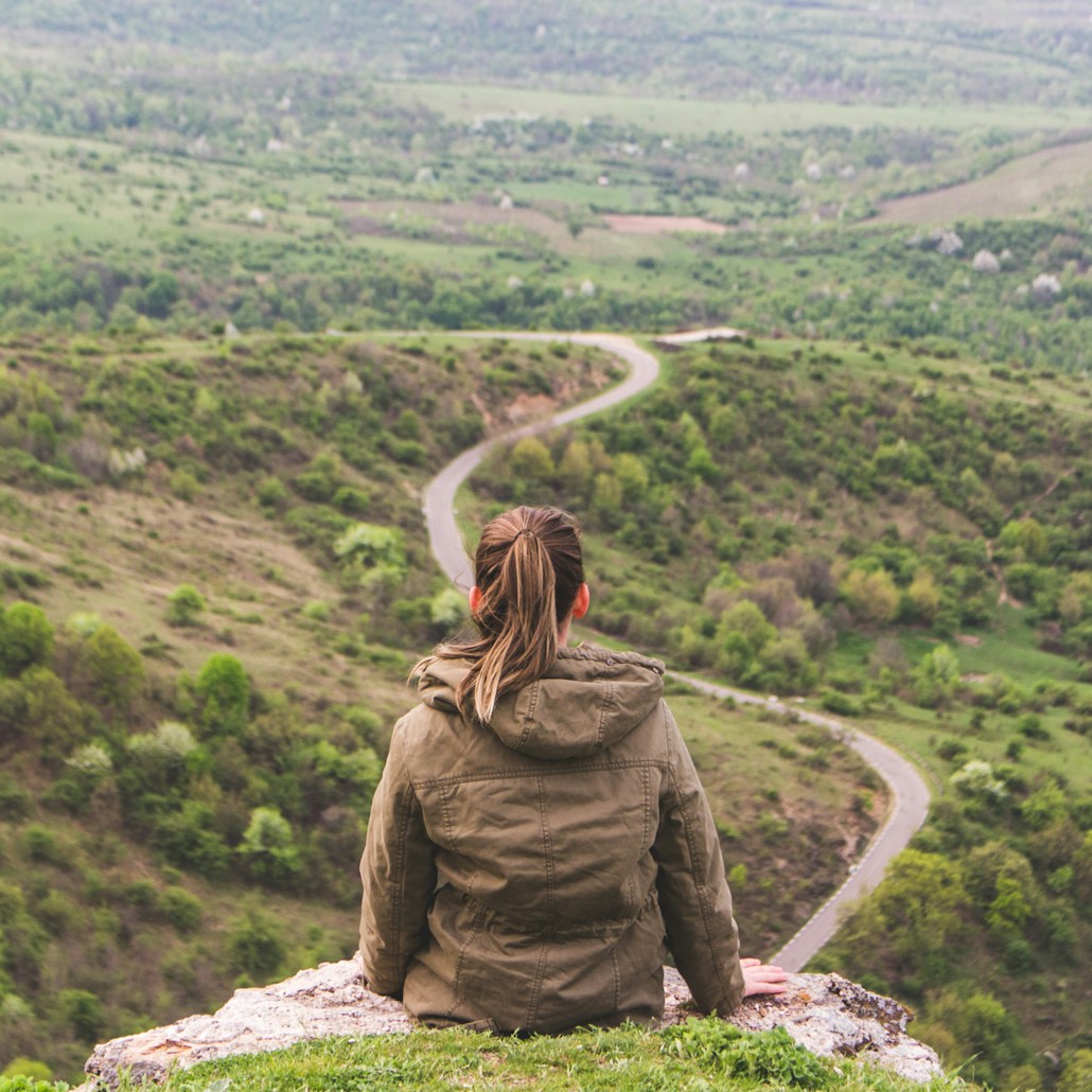 woman sitting on gray cliff