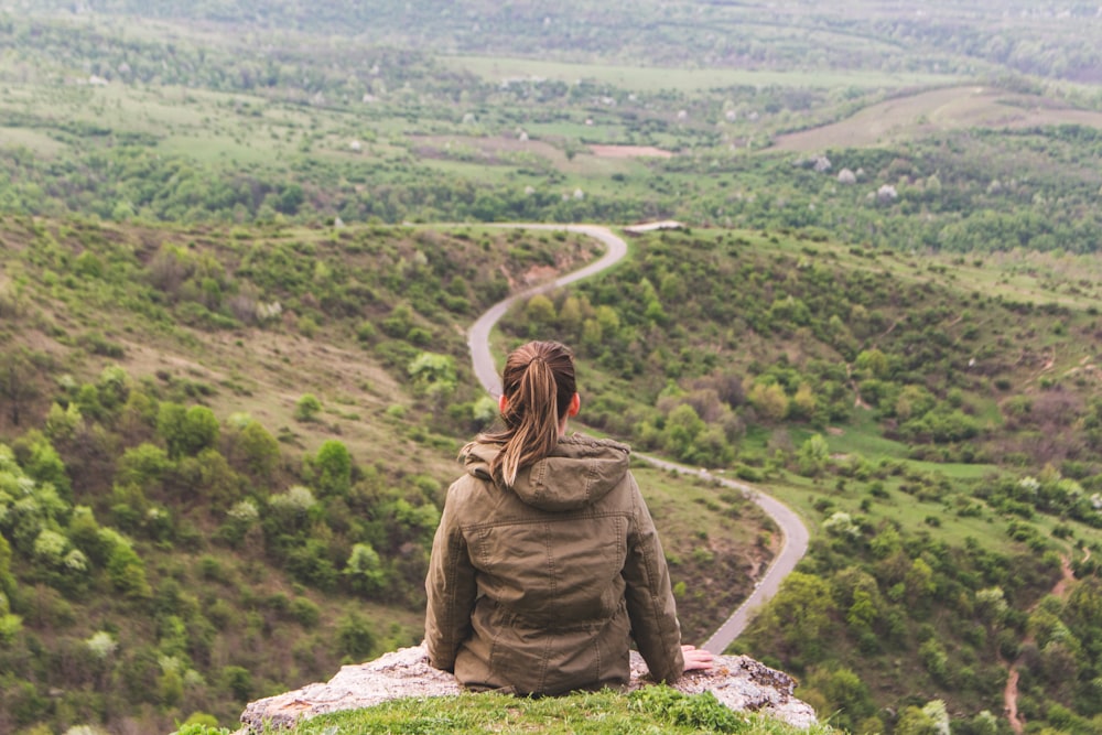 woman sitting on grey cliff