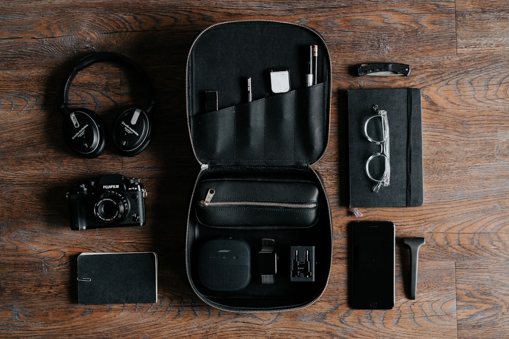 black headphones beside camera on top of wood