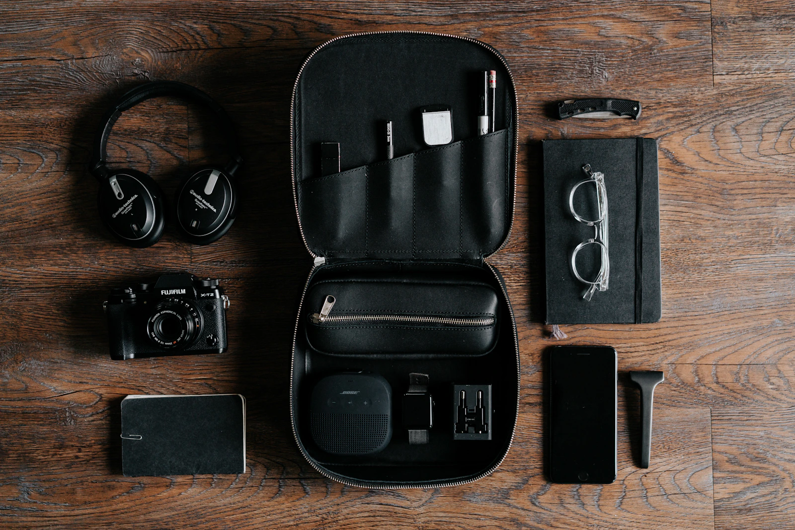 Headphones, camera and tech pouch flat lay on wood