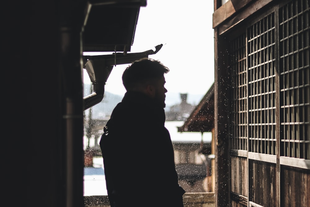 man standing under hose looking on window